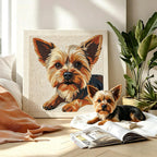 Dog sitting next to a framed portrait of a dog in a home setting with plants and a newspaper.