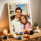 Embroidered portrait of a couple on a wooden board with yarn balls and a candle on a woven surface.