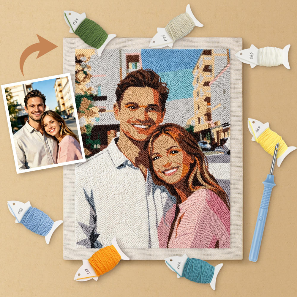 Completed needlepoint of a couple with a photo of them on the side, surrounded by yarn and tools.